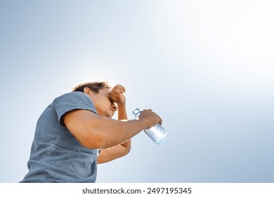 Young man drinking water from bottle feeling hot dehydrated from summer heat wave, person drinks from water bottle replenish fluids 
 - Powered by Shutterstock