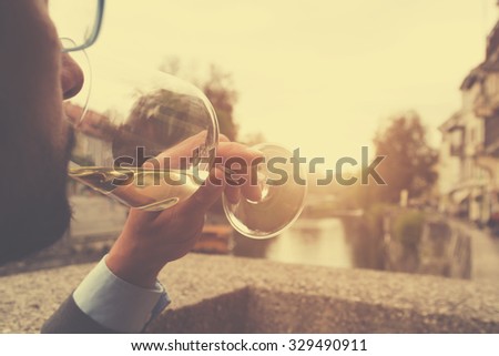 Young man drinking wine outdoors.