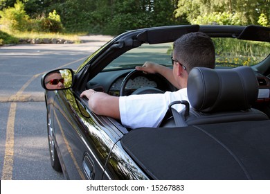 A Young Man Driving Away In His Shiny Black Convertible.