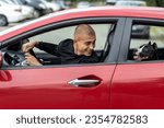 A young man driving a car has his head turned toward his dog, chatting cheerfully with him.