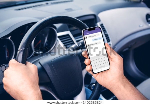 Young man driving a car with a phone\
in his hand. Don\'t text and drive. Distracted\
driving.