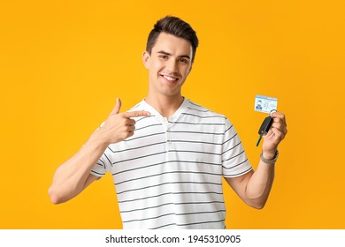 Young man with driving license and car key on color background