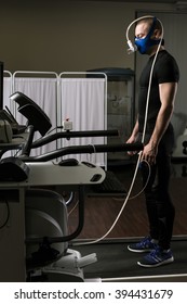 Young Man During Cardiac Stress Test Standing With Mask On Treadmill