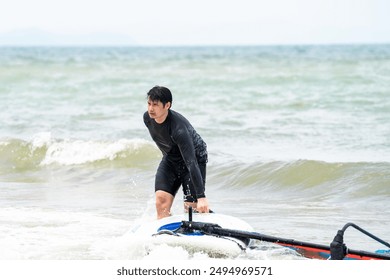 Young man earnestly practices windsurfing at the sea. - Powered by Shutterstock