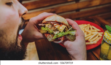 Young Man Eating A Cheeseburger. Restaurant