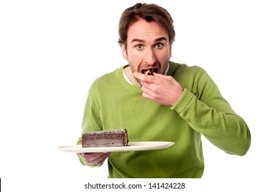 Young Man Eating Chocolate Cake In Hurry