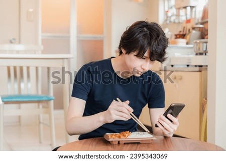 Young man eating a convenience store lunch box at home