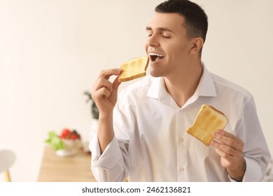 Young man eating crispy toasts in kitchen - Powered by Shutterstock