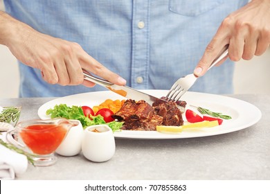 Young Man Eating Delicious Ribs In Restaurant