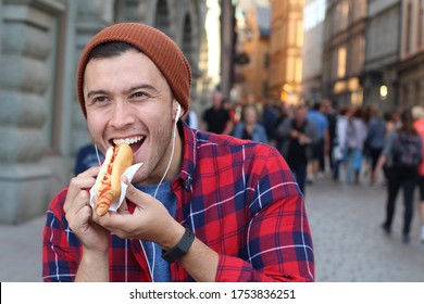 Young man eating a hot dog outdoors