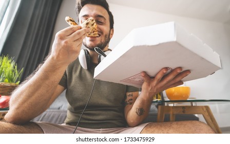 Young man eating pizza delivery at home - Happy guy having meal while playing video games in living room - Food and youth people entertainment concept 
