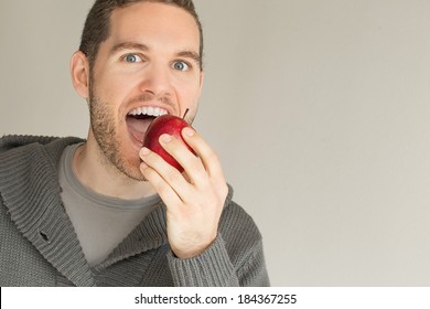 Junge Männer, die einen roten Apfel auf grauem Hintergrund essen