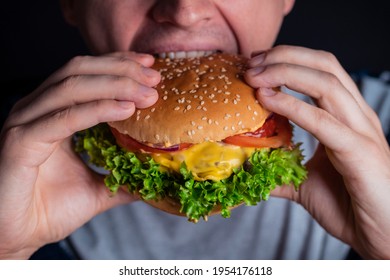 Young Man Eating Tasty Burger. Extreme Close Up. Male Bite A Cheeseburger.