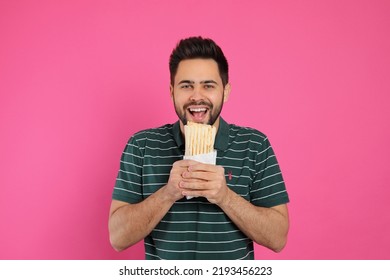 Young Man Eating Tasty Shawarma On Pink Background