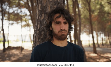 Young Man Eats Bad Tasting Food and Vomits Behind a Tree in Nature in the Nature