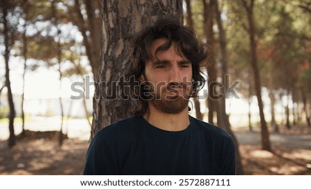 Young Man Eats Bad Tasting Food and Vomits Behind a Tree in Nature in the Nature