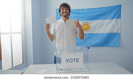 Young man in electoral room with argentinian flag giving thumbs up while holding ballot paper by a voting box. - Powered by Shutterstock