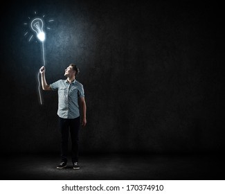 Young man and electrical bulb against dark background - Powered by Shutterstock