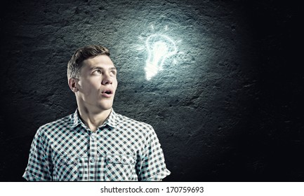 Young man and electrical bulb against dark background - Shutterstock ID 170759693