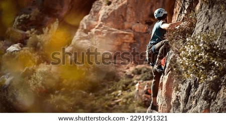 A young man is engaged in extreme sports, leads an active lifestyle, climbs a rock with climbing equipment  in the sunny day against the background of Twin Caves, Leonidio, Arcadia, Greece.