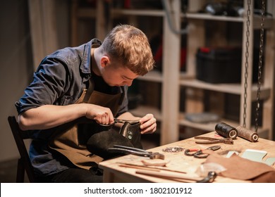 a young man is engaged in the family craft of making leather shoes in a workshop - Powered by Shutterstock