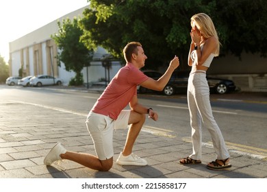 Young Man With Engagement Ring Making Proposal To His Beloved Girlfriend Outdoors. 
