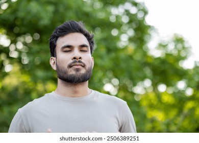 Young man engages in mindfulness and relaxation exercises, standing outdoors with eyes closed. Captures peaceful moments of meditation and wellness, highlighting focus on breathing - Powered by Shutterstock