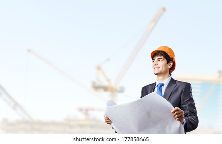 Young man engineer in helmet examining construction project
