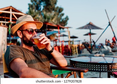 Young Man Enjoying Beer In A Beach Bar