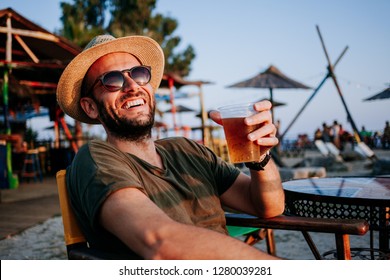 Jovem desfrutando de cerveja e pôr do sol em um bar de praia
