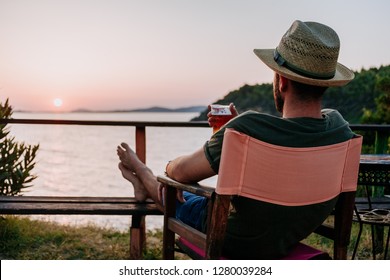 Young Man Enjoying Beer And Sunset In A Beach Bar