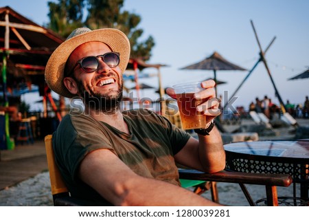 Young man enjoying beer and sunset in a beach bar