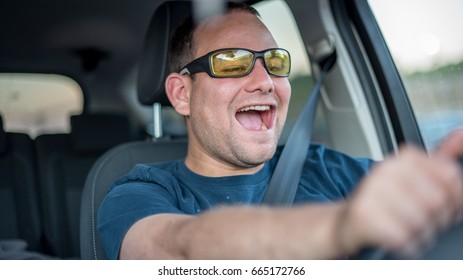 Young man enjoying car driving in sunglasses