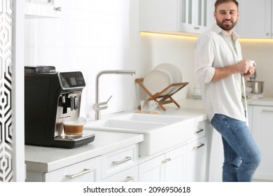 Young man enjoying fresh aromatic coffee in kitchen, focus on modern machine - Powered by Shutterstock