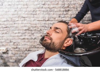 Young man enjoying hairwash at beauty salon - Powered by Shutterstock