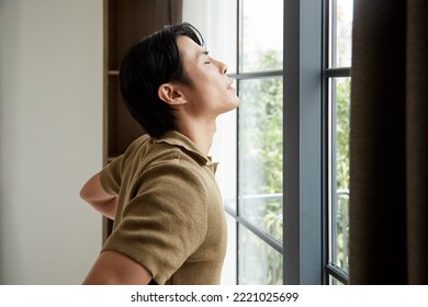 Young Man Enjoying New Day, He Is Opening Curtains And Catching Sunrays