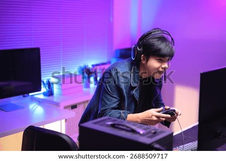 A young man enjoying playing computer games in a neon-lit room. The gaming atmosphere features vibrant colors.
