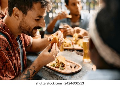 Young man man enjoying in a taco while having lunch with friends in Mexican restaurant. - Powered by Shutterstock