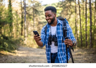 Young man enjoys hiking  and using mobile phone in nature. - Powered by Shutterstock