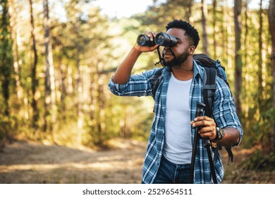 Young man enjoys using binoculars and hiking in nature.	 - Powered by Shutterstock