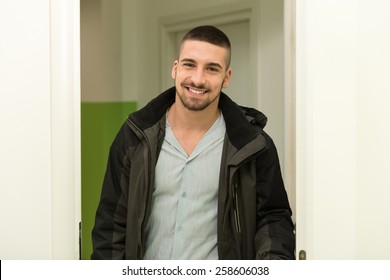 Young Man Entering Through His Front Door With A Smile On His Face