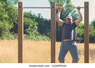 Young Man With Excess Weight Doing Pull Up Exercise On Horizontal Bar