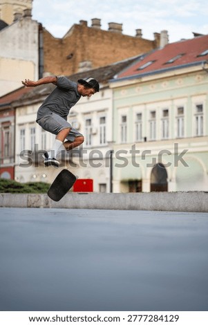 Young man executing an impressive kickflip, catching air on his skateboard in a historic city square, showcasing street culture