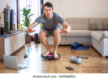 Young Man Exercising Doing Workout At Home In Front Of Laptop