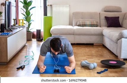 Young Man Exercising Doing Workout At Home In Front Of Laptop