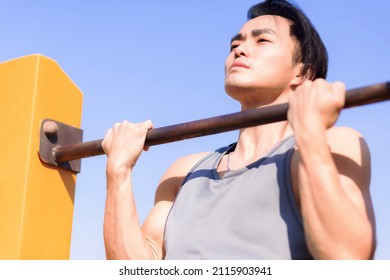 Young man exercising and holding his upper body above horizontal bar - Powered by Shutterstock