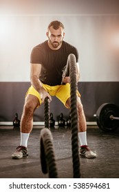 Young Man Exercising With Ropes At The Gym.