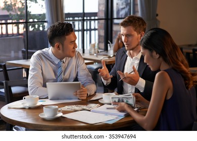 Junger Mann, der den Mitarbeitern Geschäftsidee erklärt, wenn sie im Cafe sitzen