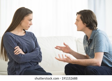 Young Man Explaining Woman While Arguing In Living Room