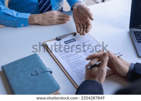 A young man explains his history to a business manager sitting in an interview. Contract recruitment and business employment Send resumes to recruiters for background checks.